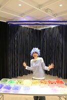 イベントで使用する舞台美術の一部の前でワークショップで作成する帽子をかぶった長峰麻貴。