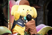 ハイタッチするポムポムプリン（左）と谷川康太役の北川尚弥（右）。