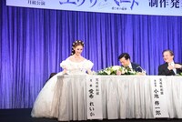 宝塚歌劇月組「ミュージカル『エリザベート―愛と死の輪舞（ロンド）―』」制作発表会より、ドレスのボリュームでなかなか着席できない愛希れいか（左）と、心配してのぞき込む小池修一郎（右から2番目）。