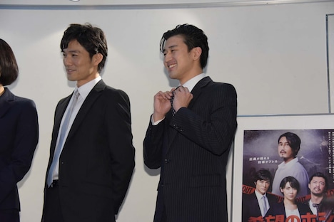 金児憲史のものだというネクタイを示す岩永ジョーイ(中央)。