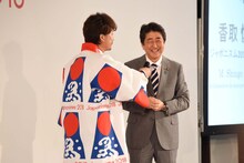 「ジャポニスム2018：響きあう魂」出陣祝賀会より、香取慎吾（左）と、「法被を着てハッピー！」とマイク越しに冗談を飛ばす安倍晋三内閣総理大臣（右）。