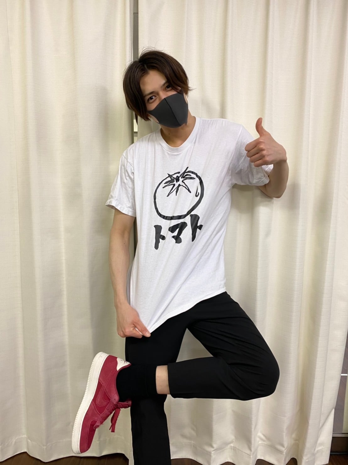 モノトーンに筆文字が潔い、トマトのTシャツでポーズ。トマトのイラストは白黒だが、シューズはレッドで元気よく。
