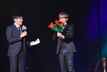 成河から5分で教わったという“花が飛び出す手品”について解説する山寺宏一（右）。