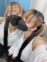 鏡越しに視線を送る仲。ツートンカラーのヘアスタイルが白いトップスに映える。