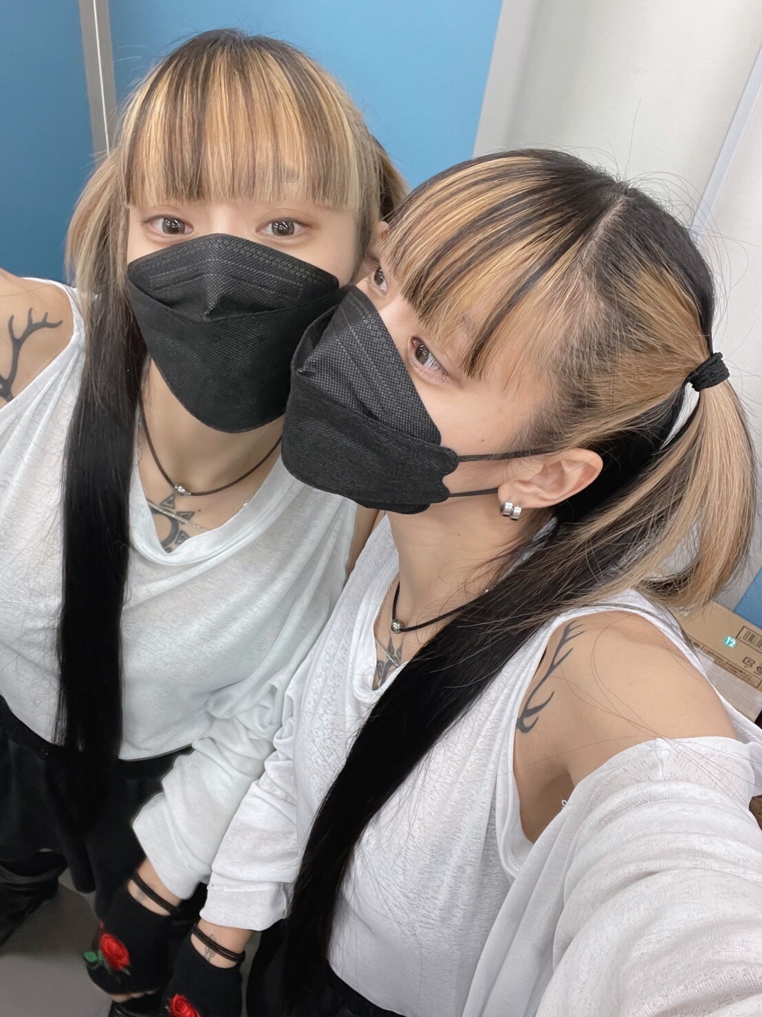 鏡越しに視線を送る仲。ツートンカラーのヘアスタイルが白いトップスに映える。