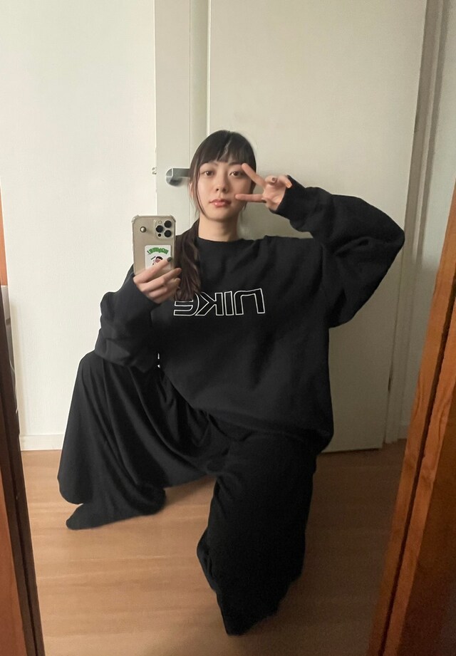 スウェットのロゴが目を引くブラックコーデ。ワイドパンツがリラックスしたムードを作り出す。