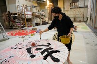 番傘に文字入れする尾上右近。