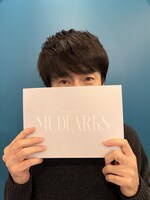 「MUDLARKS-マッドラークス-」の公演パンフレットと共に、松田誠。