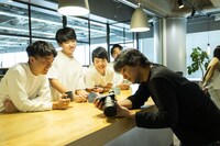 写真を楽しげに確認するRevieの面々と竪山隼太（右）。（撮影：平岩享）