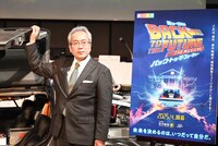 タイムマシン・デロリアンの前でポーズを取る、劇団四季の吉田智誉樹代表取締役社長。