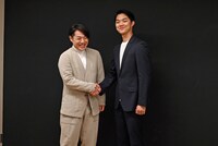 カメラマンからの「握手をしてください」というリクエストに応えて握手するも、思わず笑ってしまう中村鷹之資（左）と野村裕基（右）。
