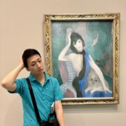 表情と仕草を完コピするヨネキチ・シャネル。脇には、犬の代わりに携帯電話を挟んで。