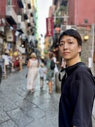 ナポリのポップな街並みを背景に、佇む米吉。