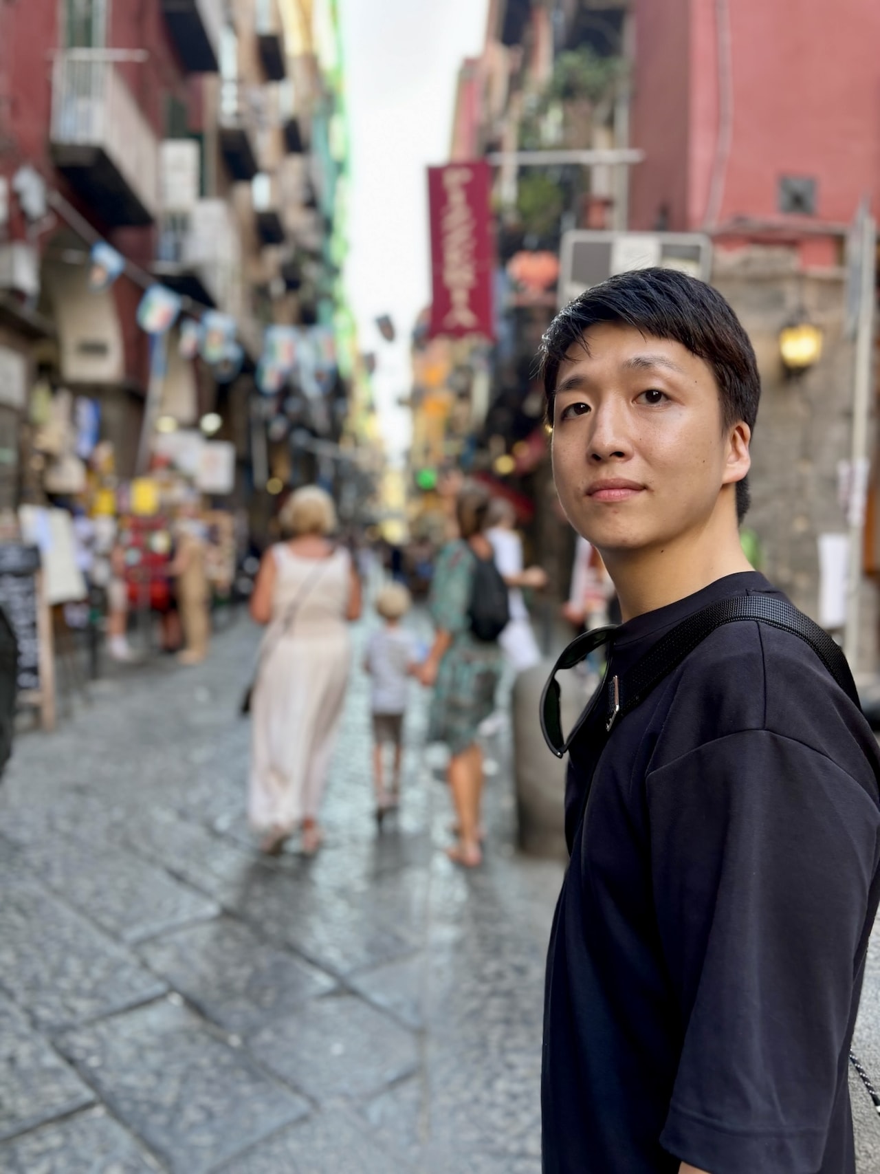 ナポリのポップな街並みを背景に、佇む米吉。