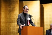 「緊張で脚が震える」と言い、演台に掴まる緒方晋。