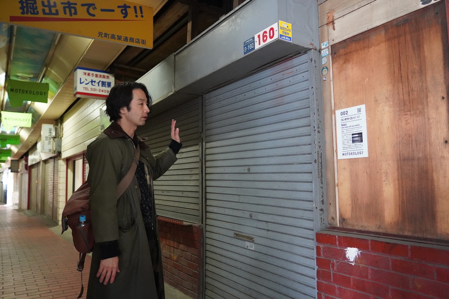 contact Gonzoの作品を紹介する森山未來。シャッターに設けた穴から老舗洋菓子店の元店舗を覗き見るインスタレーション作品だ。