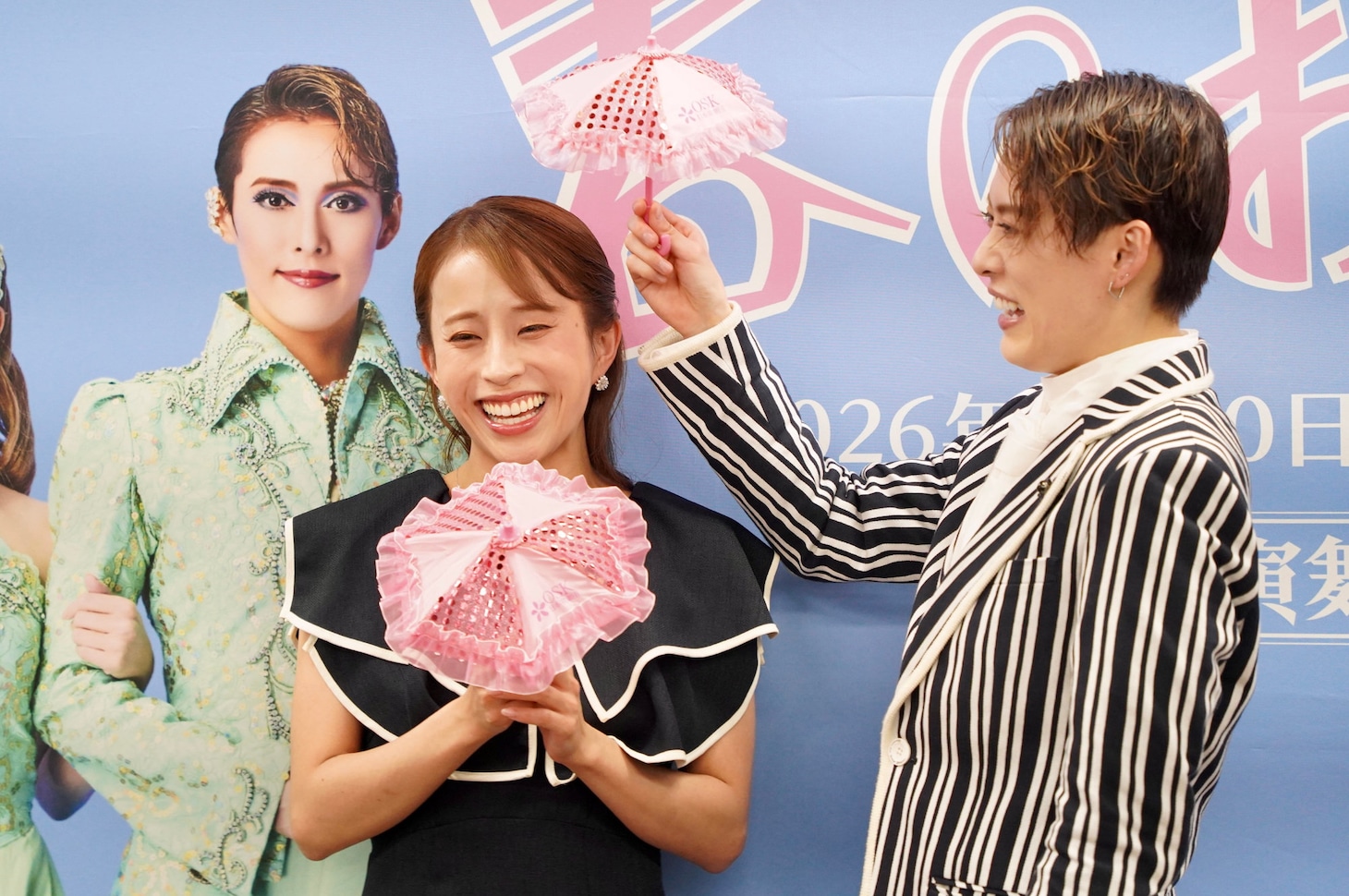 翼和希（右）に桜ミニパラソルをさされて、照れ笑いする千咲えみ（左）。