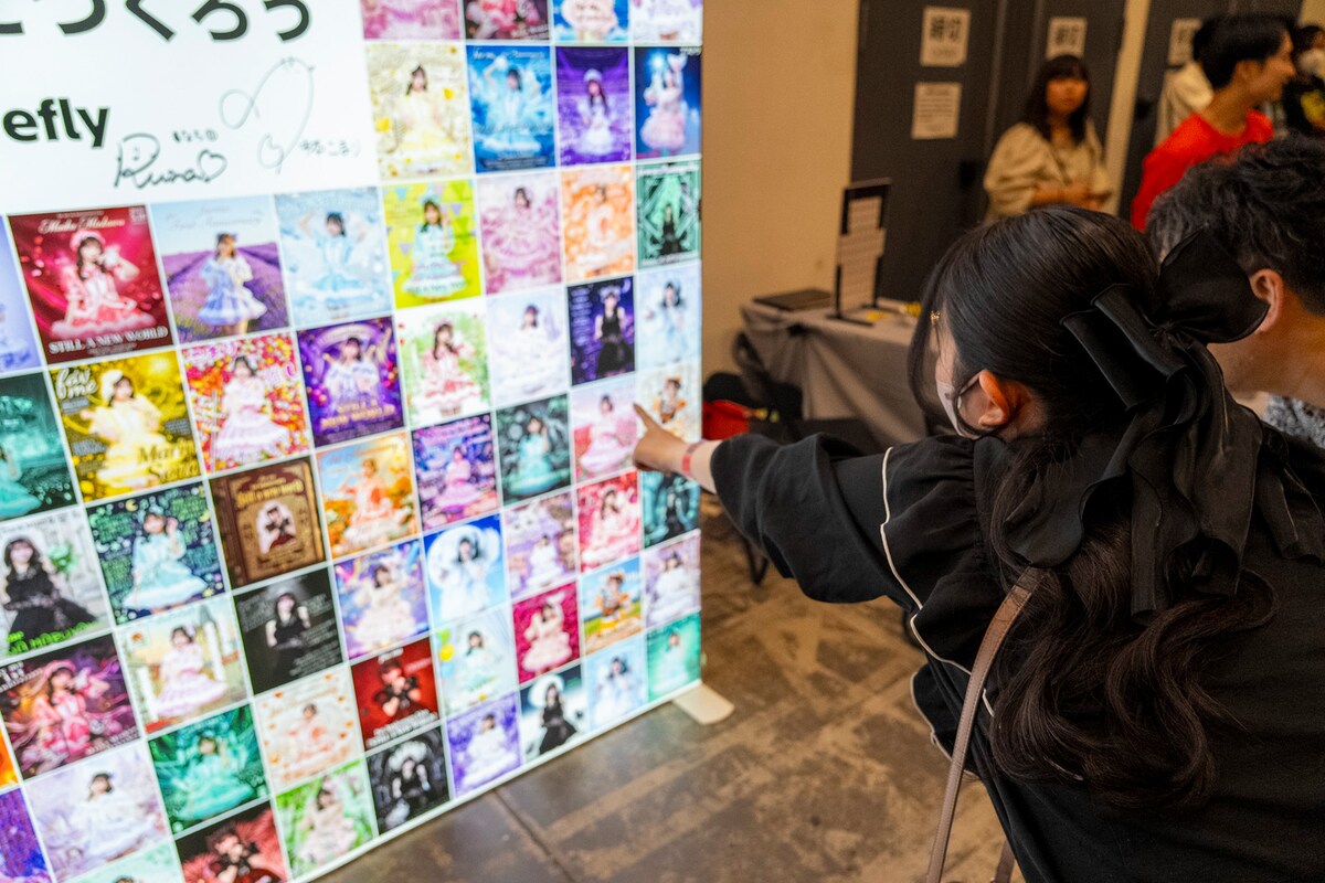 祝福ボードに展示された作品を指差すfav meファン。