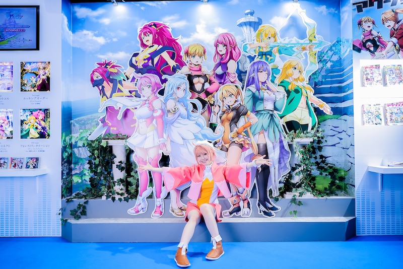 キャラクターのパネルの前でポーズを決める柏木れに。