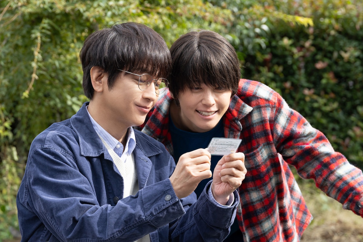 ドラマ「ぼくたちん家」場面写真。知人からパートナーシップ届受領証カードを見せてもらい、興味津々の波多野玄一（演：及川光博 / 左）と作田索（演：手越祐也 / 右）