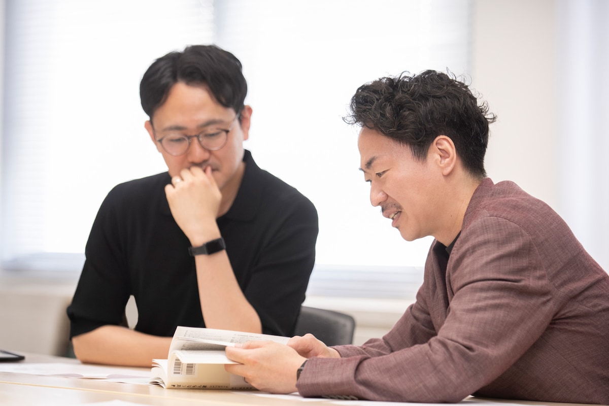 ドラマ「ぼくたちん家」のシナリオブックを読む、演出の鯨岡弘識（左）とインクルーシブプロデューサーの白川大介（右）