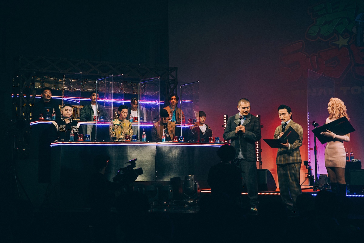 審査員席上段左からNAIKA MC、DJ TATSUKI、Gucci Prince、KEN THE 390、下段左からT-Pablow、呂布カルマ、S-kaine、Authority。右側はMCを努めたカミナリとえまぽち。