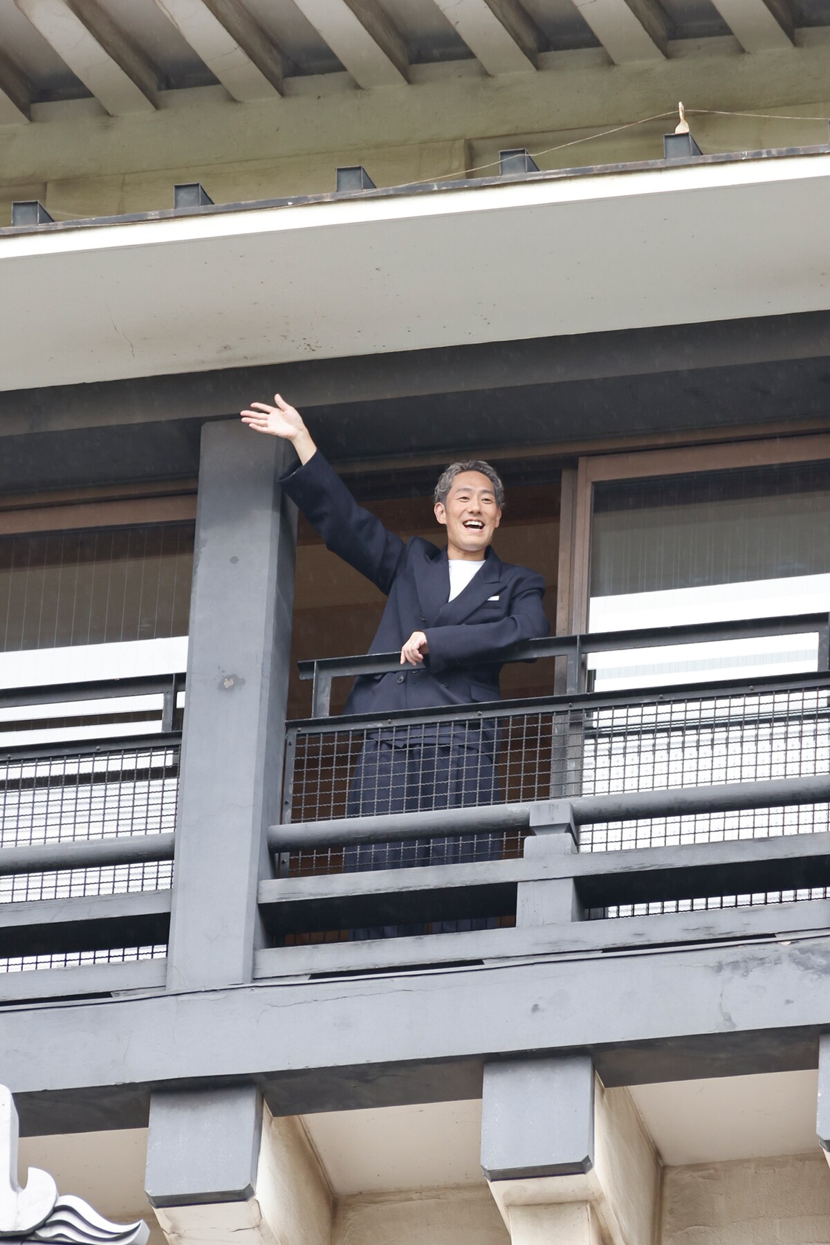 小倉城の天守閣から、報道陣に向かって手を振る中村勘九郎。