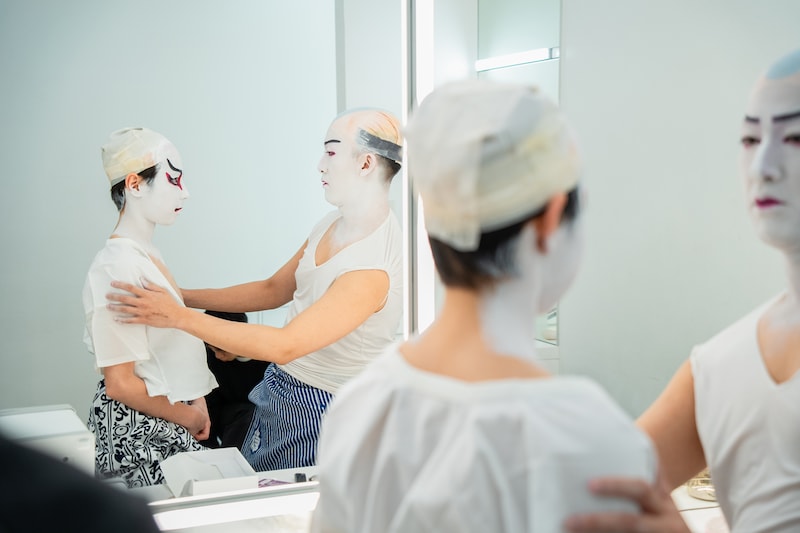尾上眞秀（左）の化粧の様子を確認する尾上右近（右）。