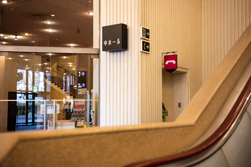 中ホールのサインの後ろには懐かしい公衆電話のマーク。公衆電話は現役。