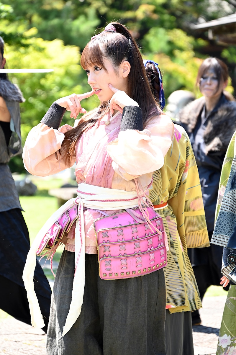 野武士に囲まれながらかわいらしいポーズを決める佐々木彩夏。