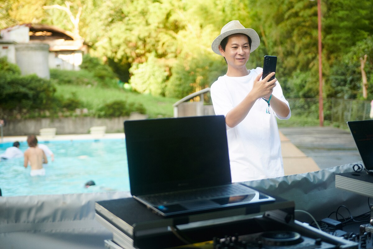 「moto g52j 5G Ⅱ」でプールサイドのDJを撮る津田昌太朗氏。