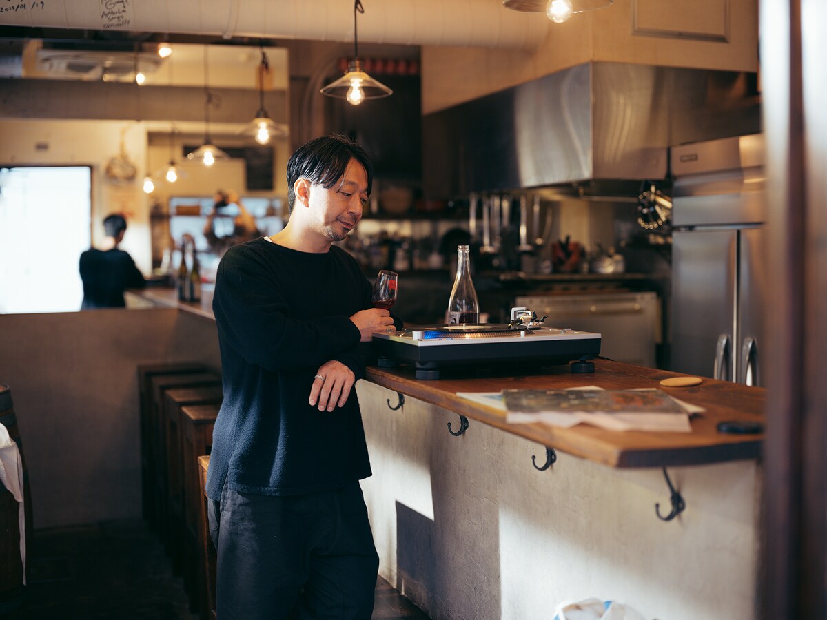 ワインを片手にレコードを楽しむ齊藤輝彦。