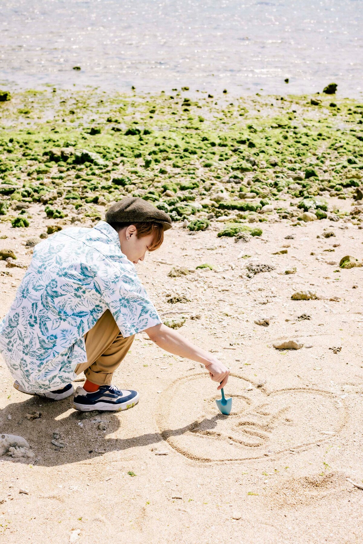 百名ビーチの砂浜に文字を書くGEN（B, Vo）。