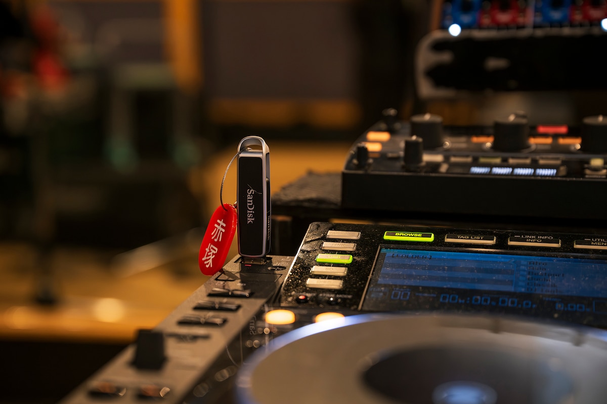 「CDJ-2000NXS」に挿された「SANDISK DJフラッシュドライブ」。こちらは現在「赤塚」というタグを付けて使用されている。