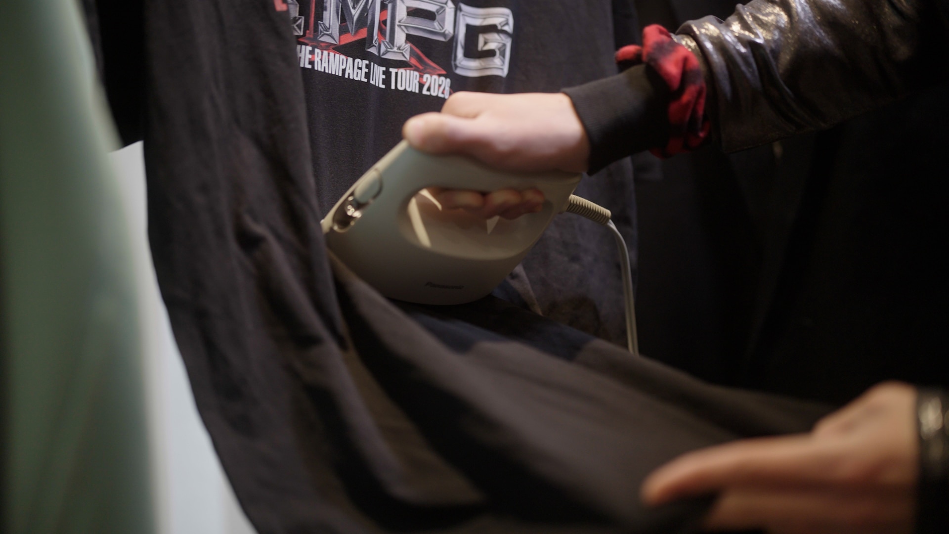 auskouのアドバイスを受けTシャツのシワをするするとのばしていく長谷川慎。