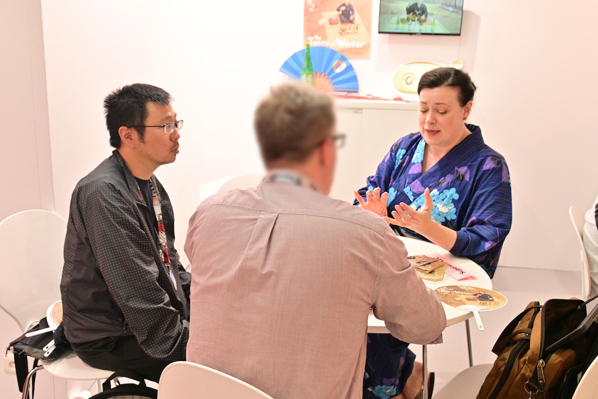 MIFAの東京都ブースで海外のバイヤーにプレゼンテーションを行う大神田リキ（右奥）と中島良（左）